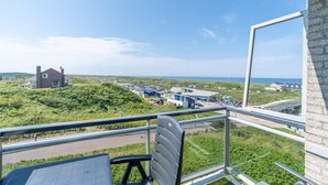 Un balcon donnant sur une zone côtière, avec vue sur un parking et des bâtiments.
