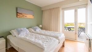 Una stanza con due letti, un quadro appeso al muro, una finestra con tende e vista sull'esterno.