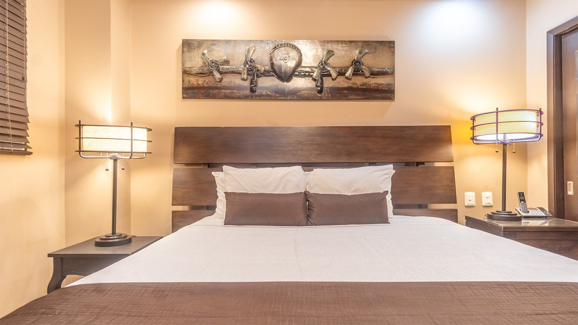 Ein Hotelzimmer mit einem großen Bett, zwei Nachttischlampen, einem Kopfteil und einem an der Wand befestigten Kunstwerk.