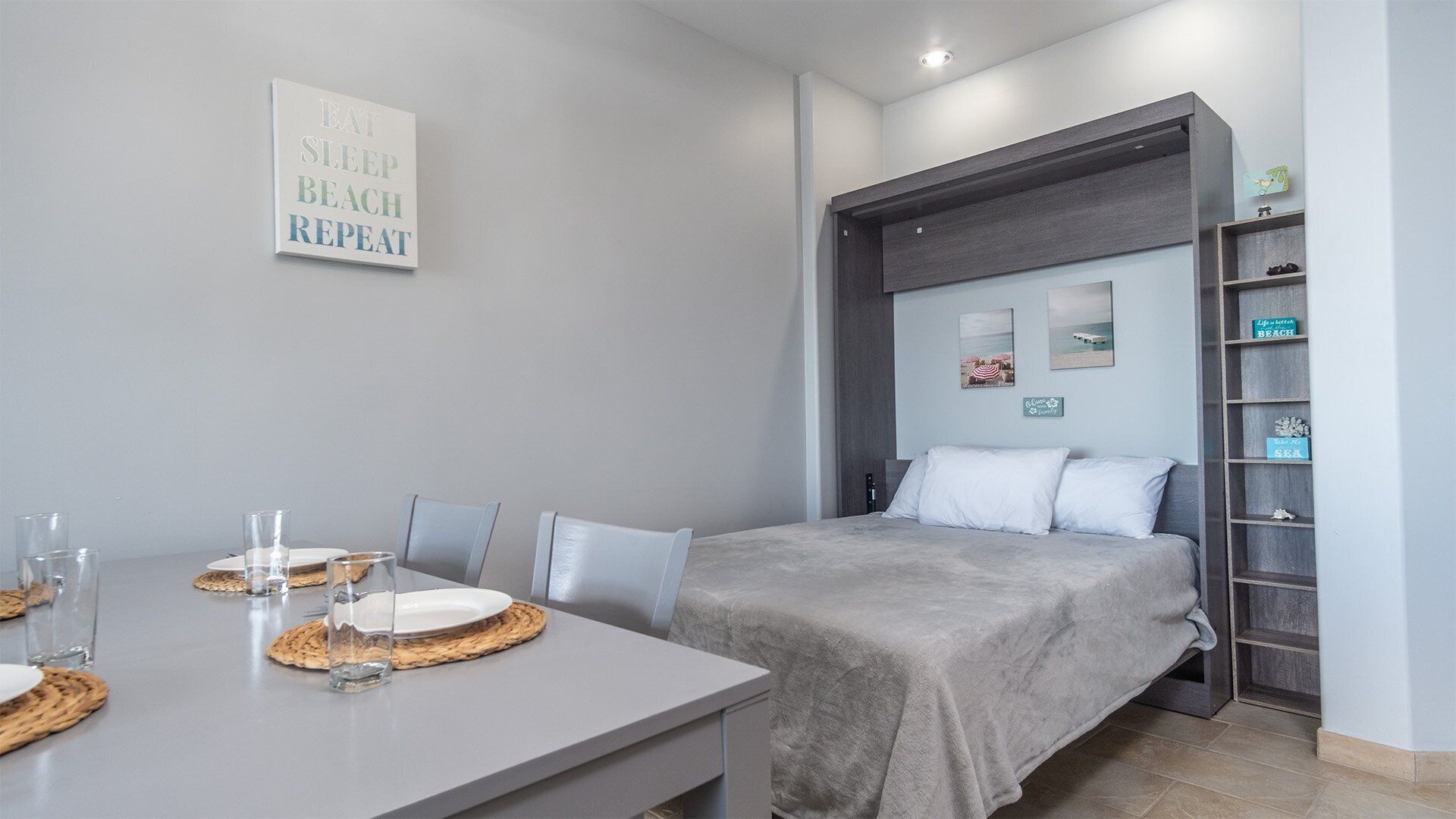 A modern bedroom with a bed, bedside tables, a bedside shelf, and a wall-mounted sign.