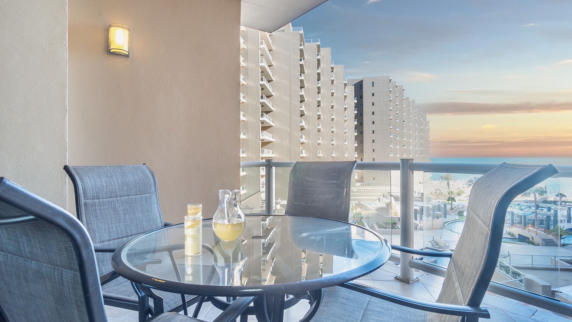 Een balkon met een glazen tafel, twee stoelen en een decoratieve muur.