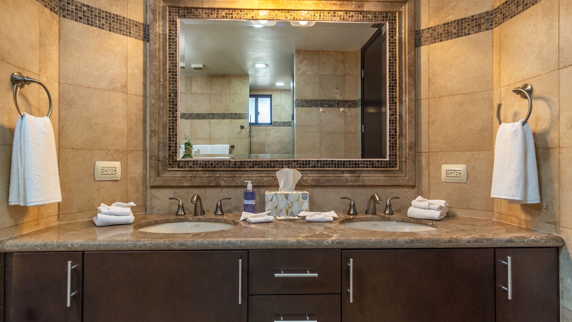 A bathroom with two sinks, a large mirror, and a towel rack.