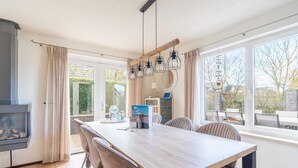 Ein moderner Essbereich mit einem langen Holztisch, gepolsterten Stühlen und Pendelleuchten.