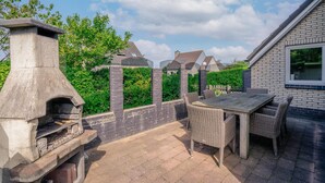 Eine Terrasse im Freien mit einem Steingrill, Korbmöbeln und einer Ziegelwand.