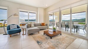 A spacious living room with a sofa, a coffee table, and a floor lamp. Large windows offer a view of the outdoors. - Grand Marina Penthouse (Playa Flamingo)