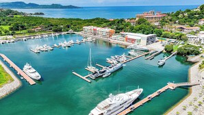A marina with multiple boats docked, a large cruise ship, and buildings in the background. - Grand Marina Penthouse (Playa Flamingo)