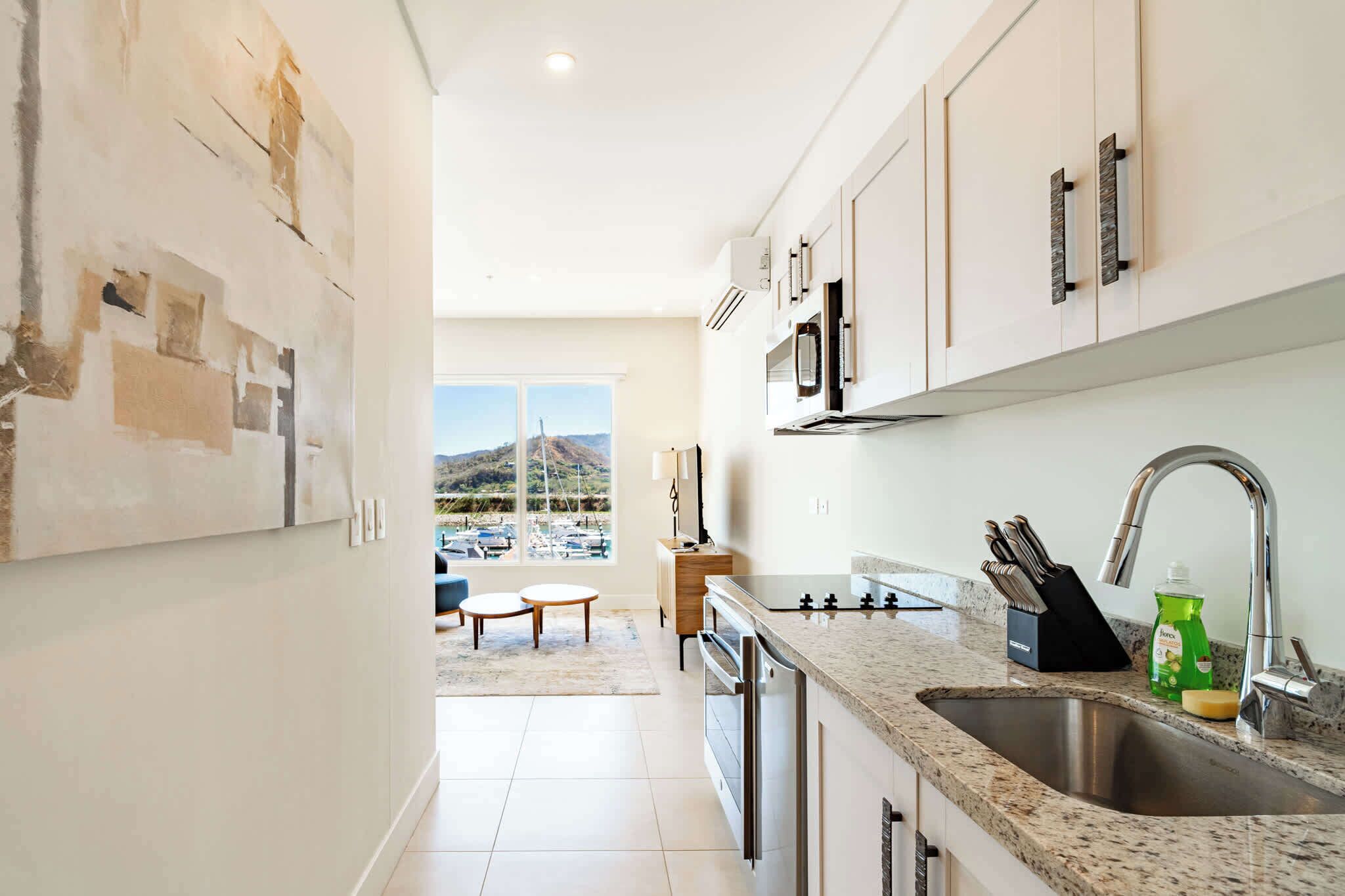 A modern kitchen with a large window, a dining area, and a view of a parking lot.