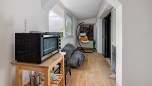 Ein gemütlicher Wohnraum mit Fernseher auf einem Holztisch, einer Couch und einem Sessel mit Kissen.