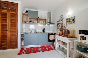 Une cuisine avec des meubles en bois, un tapis rouge et divers appareils électroménagers.