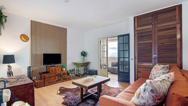 Ein Wohnzimmer mit Fernseher, Holzpaneelausschlag, Sofa und Blick durch eine Tür.