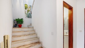 Eine Treppe mit Marmorstufen, die zu einem Badezimmer mit Holztür führt.