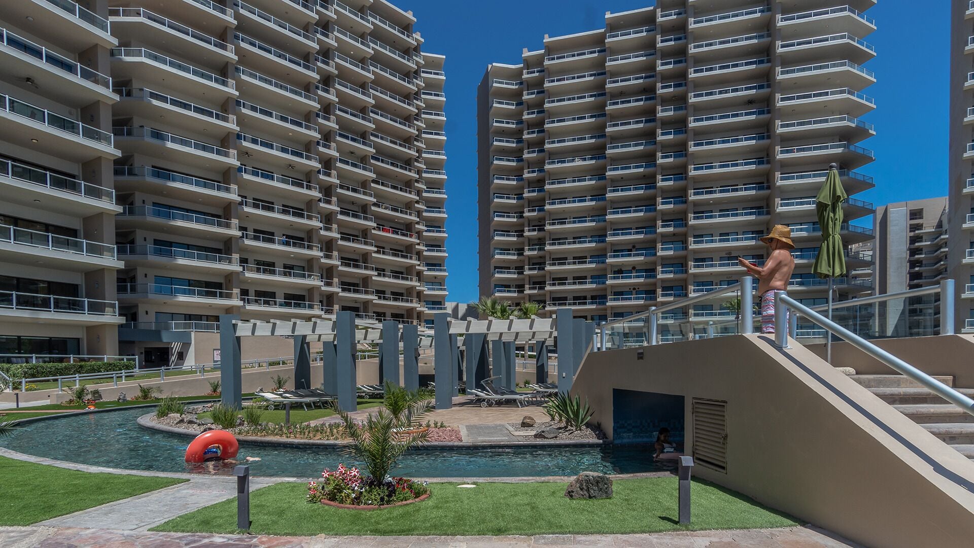 Un edificio residencial de gran altura con varios balcones, piscina y un jardín ajardinado.