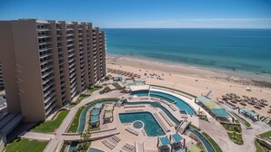 A high-rise hotel with a large pool area, beach access, and ocean views.