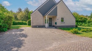 Une maison de plain-pied avec un toit en pente, une porte d’entrée et une petite fenêtre.