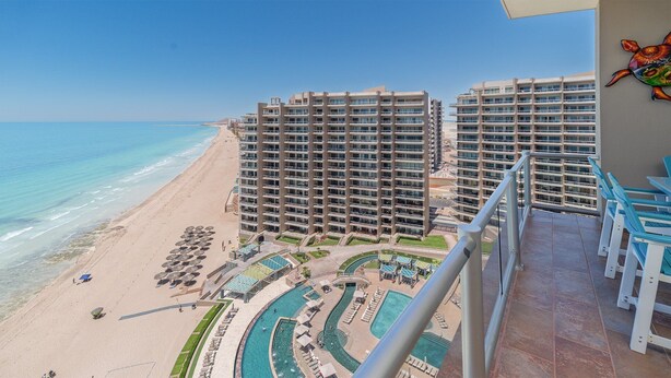 A high-rise hotel with multiple balconies overlooking a beach and a pool area. - Las Palomas Beach and Golf Resort (Puerto Peñasco)