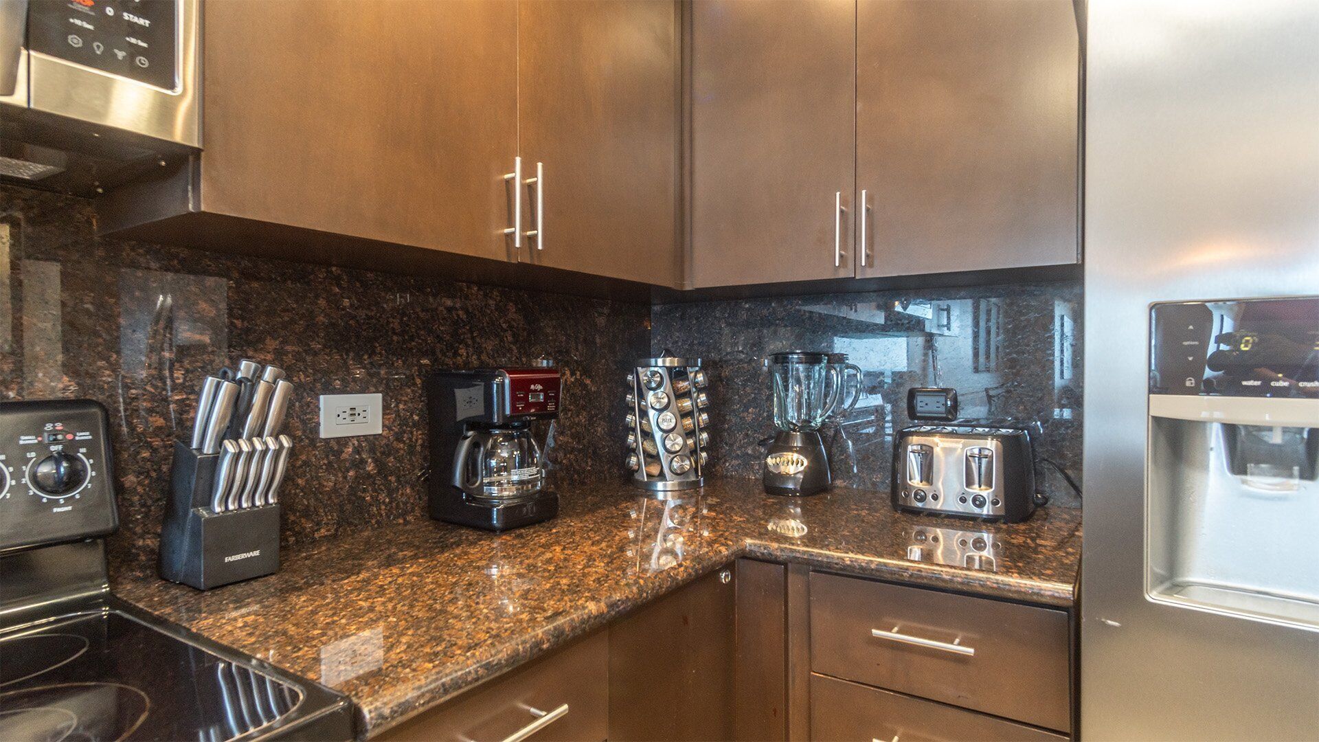 A modern kitchen with granite countertops, stainless steel appliances, and wooden cabinets.
