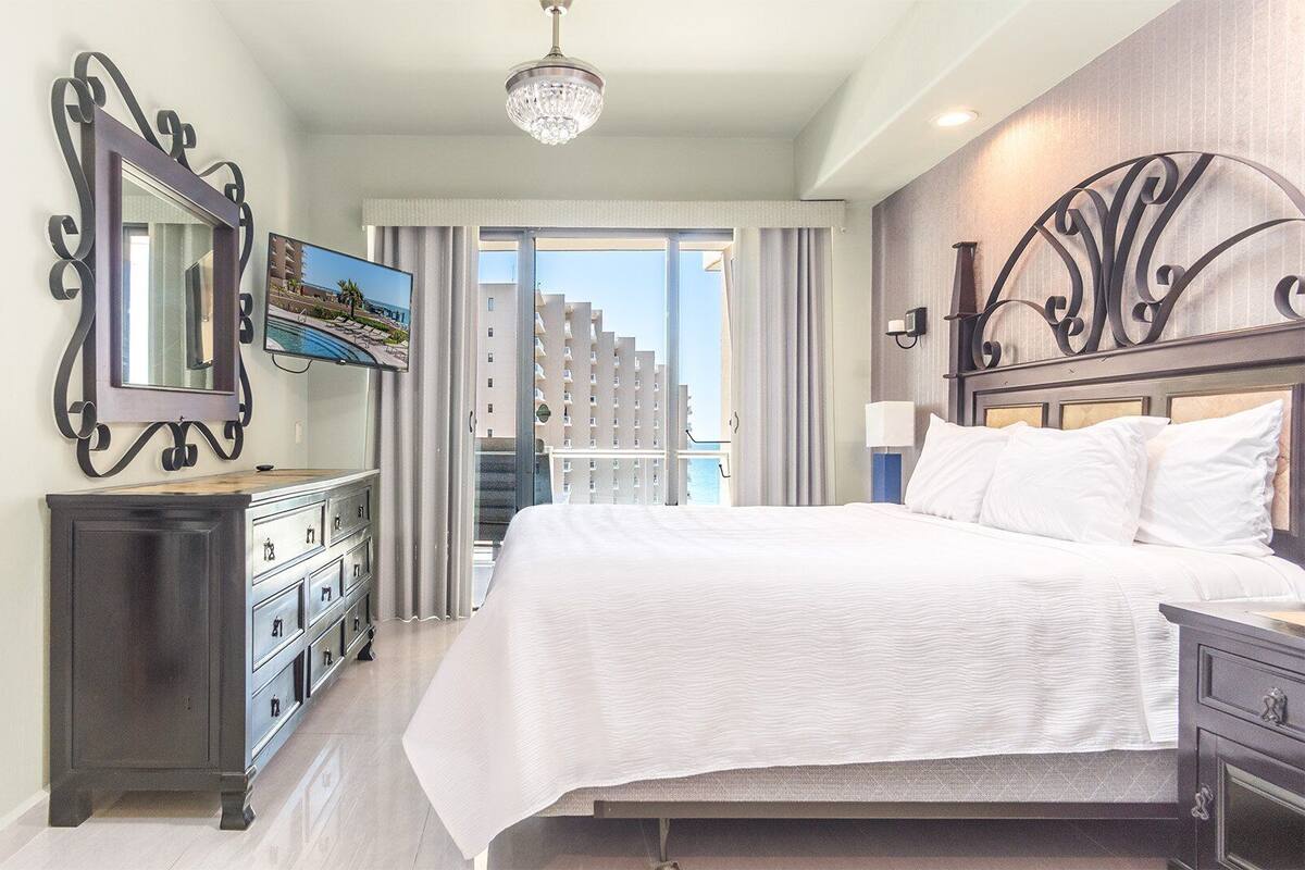Een hotelkamer met een groot bed, een kaptafel, een spiegel en een televisie.