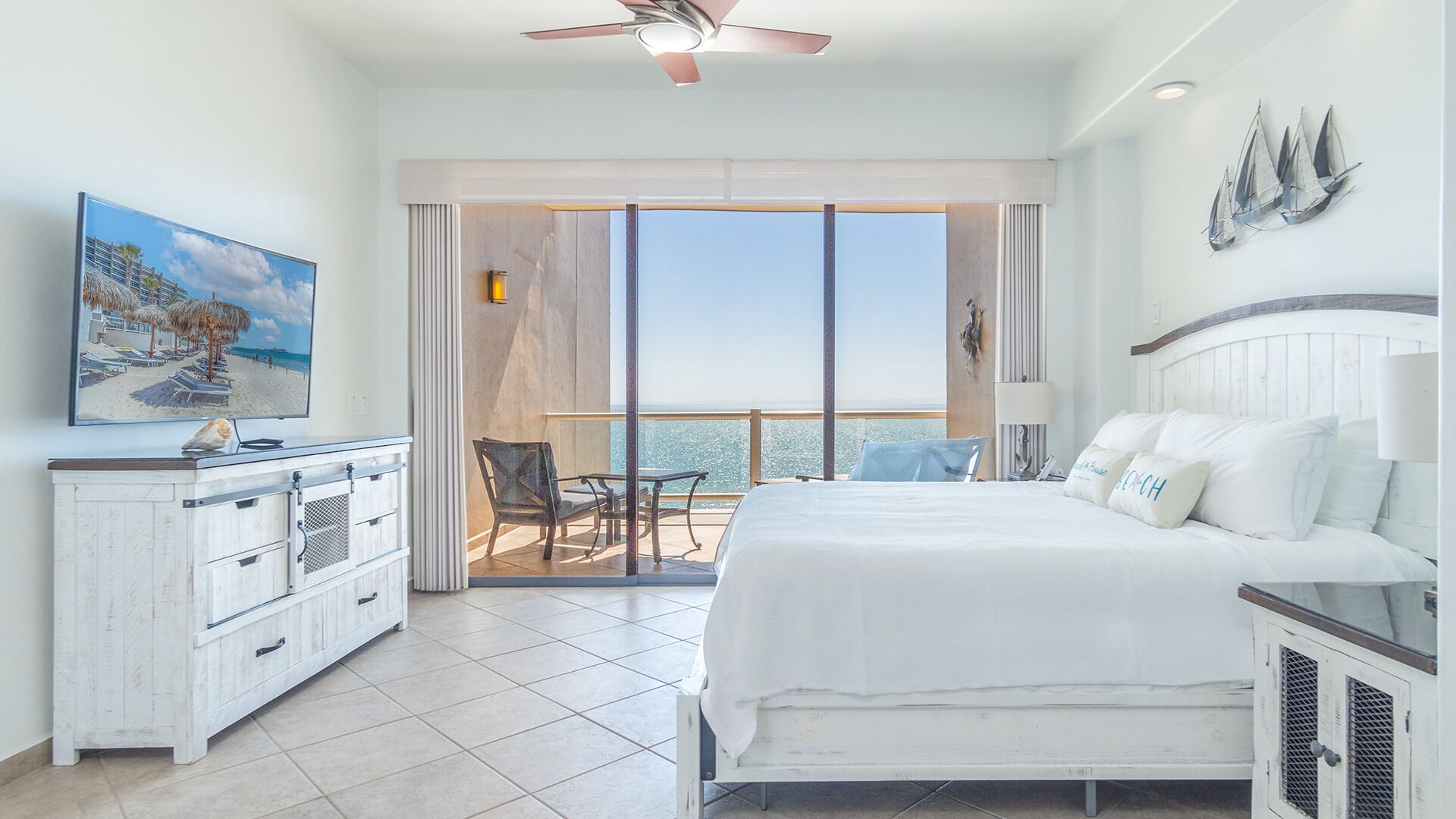 A hotel room with a large bed, a desk, a chair, and a view of the ocean.
