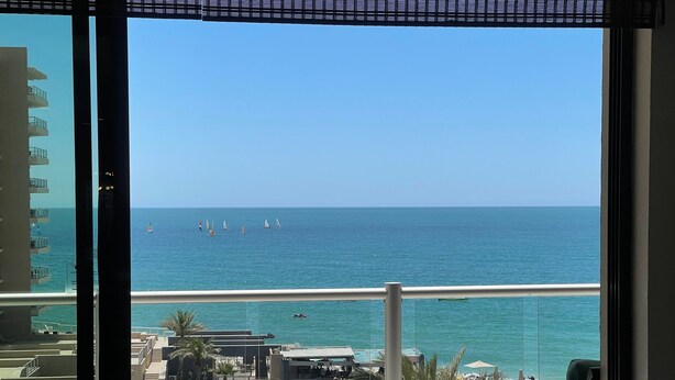 A balcony with a view of the sea, a pool area, and a building in the background. - Las Palomas Beach and Golf Resort (Puerto Peñasco)