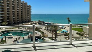 A hotel with a pool area, a view of the ocean, and a high-rise building in the background. - Las Palomas Beach and Golf Resort (Puerto Peñasco)