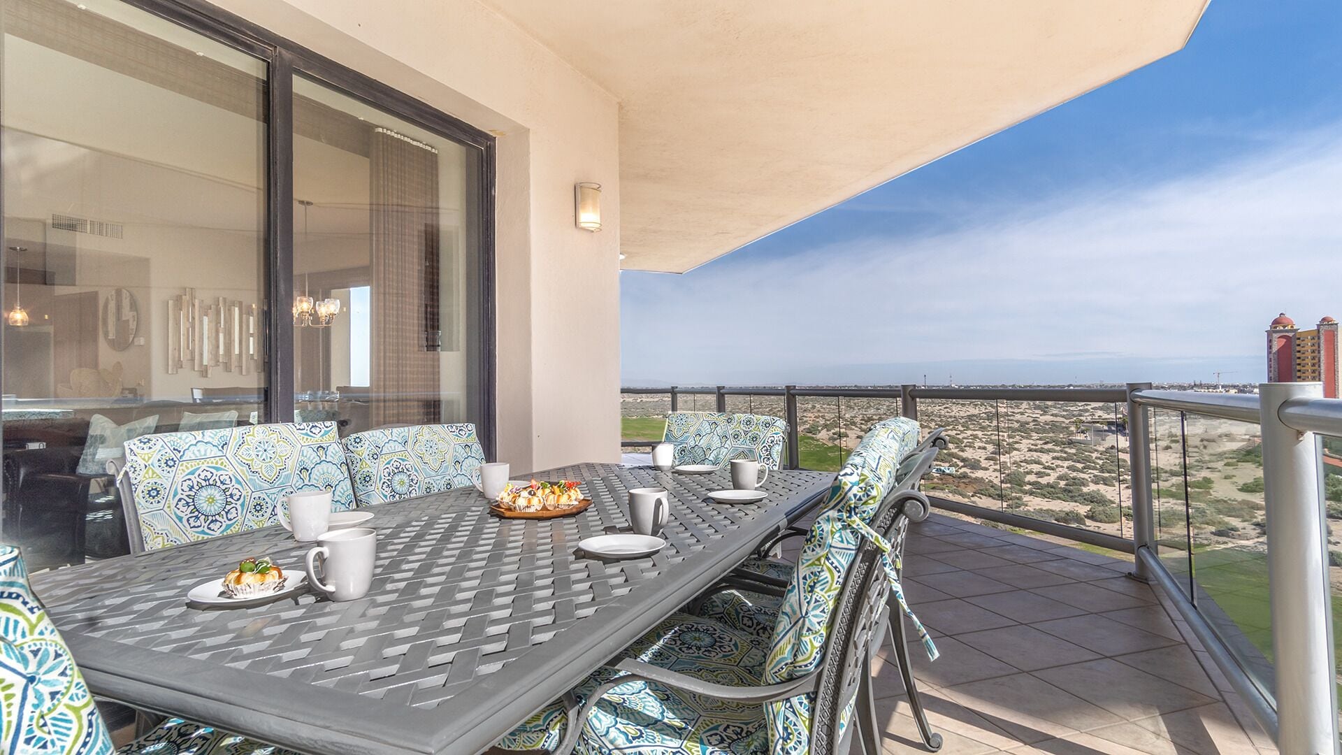 A dining area with a table set for two, outdoor seating, and a view of the landscape.