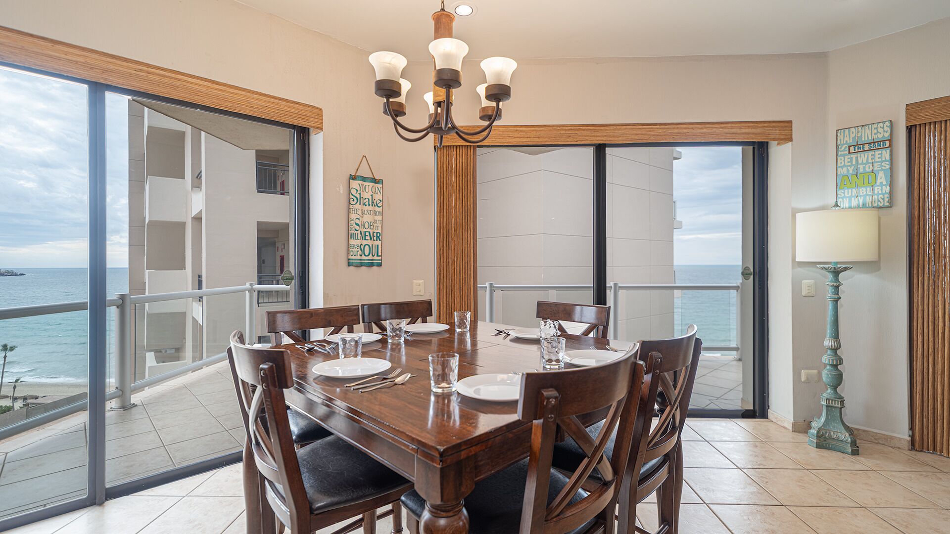 A dining area with a table set for four, overlooking a balcony with a view of the sea.