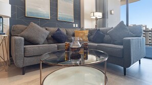 Un salon moderne avec un canapé gris, une table basse en verre et une théière.