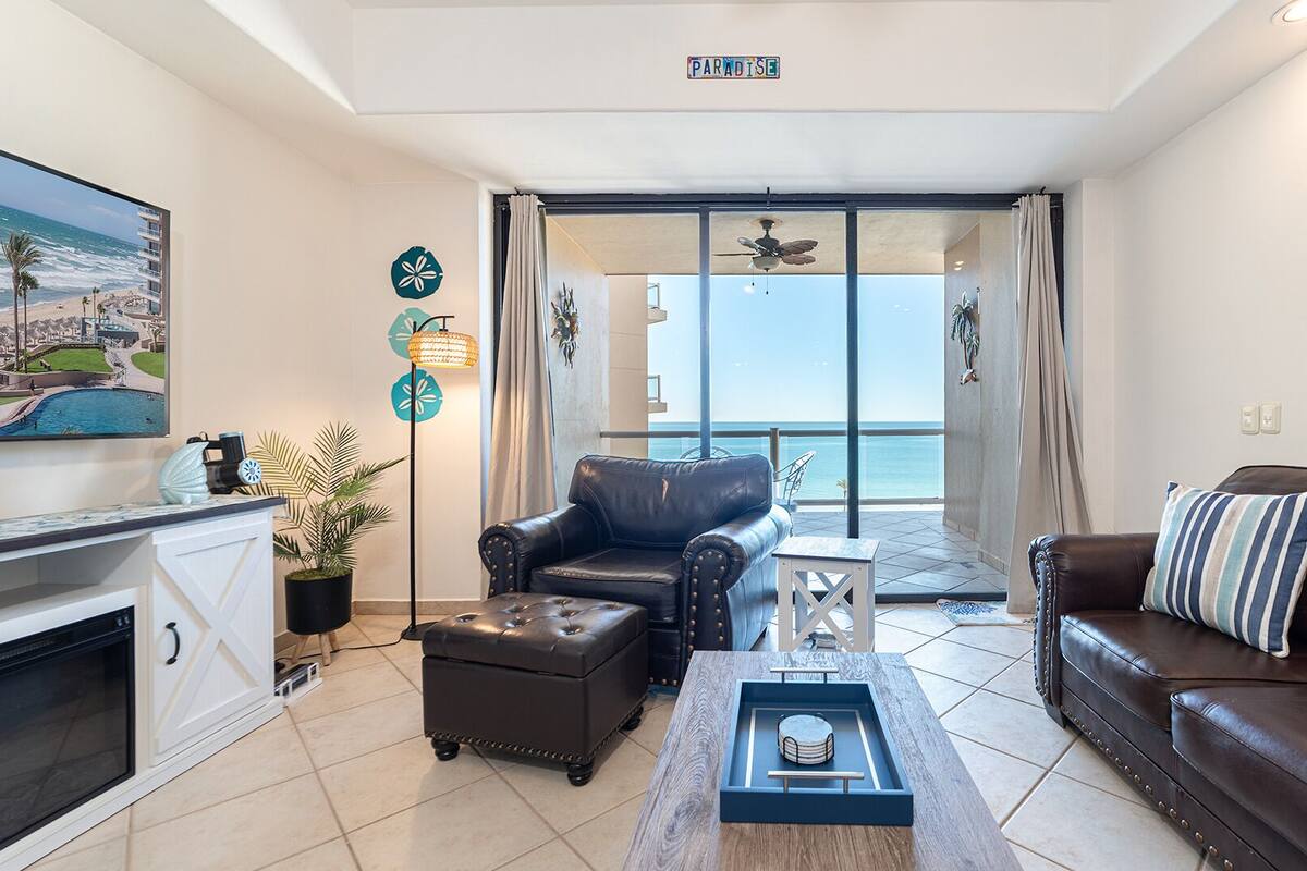 A modern living room with a view of the ocean, a fireplace, and a balcony with a view.