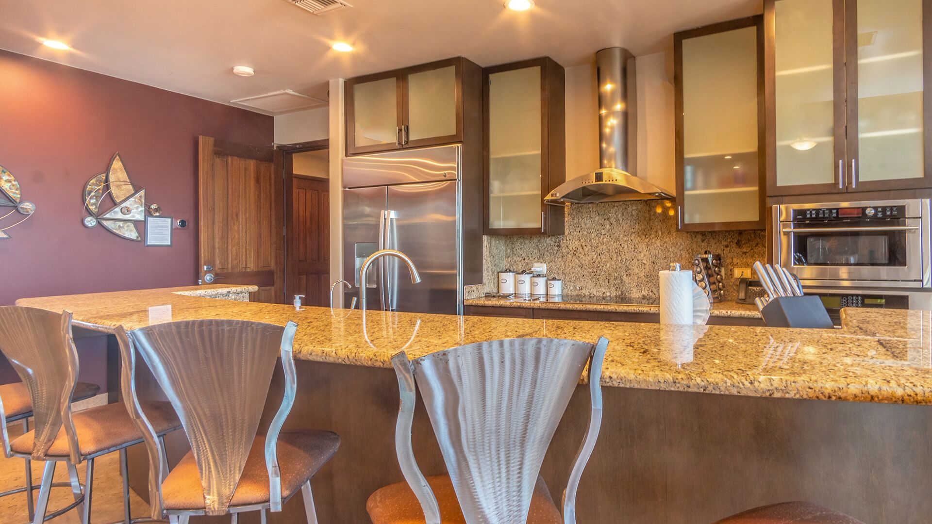 A modern kitchen with granite countertops, stainless steel appliances, and a central island with bar stools.