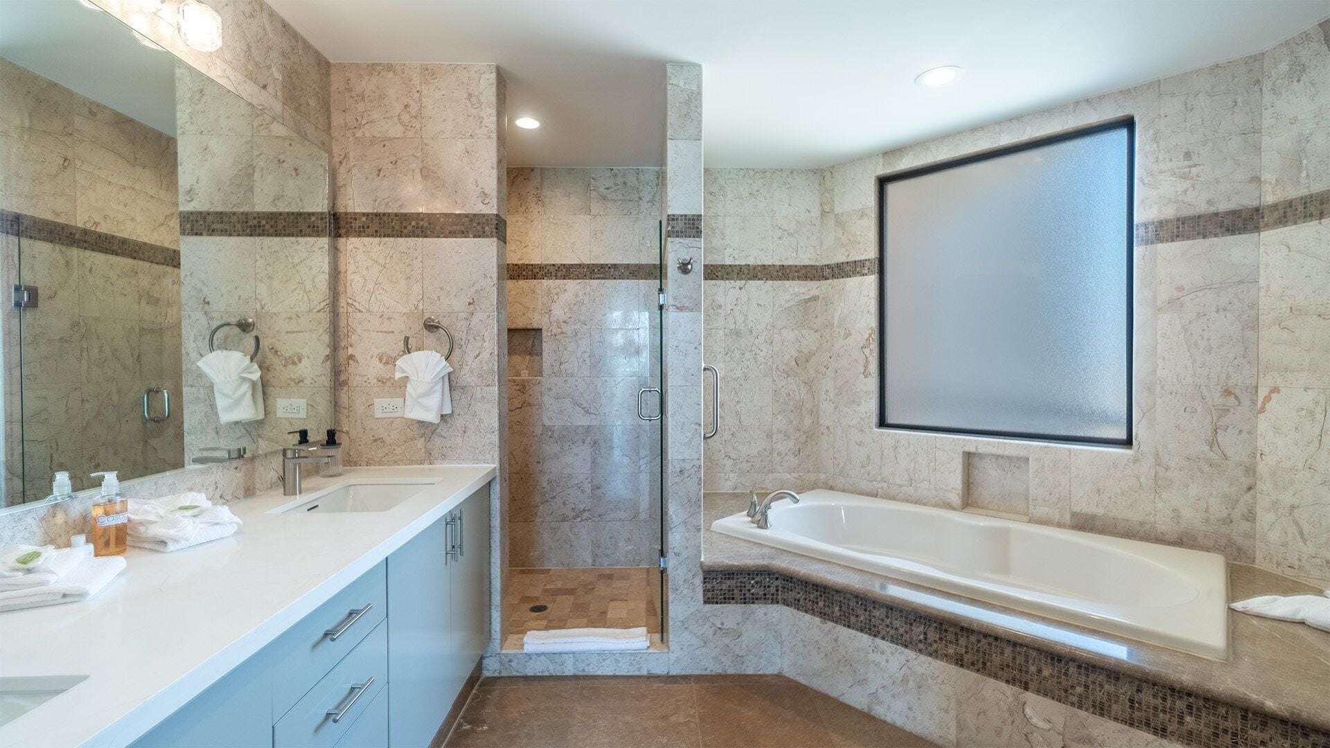 Un baño moderno con ducha envuelta en vidrio, un espejo grande y una bañera independiente.