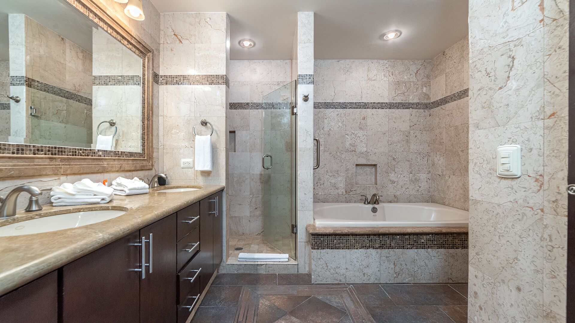 A modern bathroom with a double sink, a large mirror, a walk-in shower, and a freestanding bathtub.