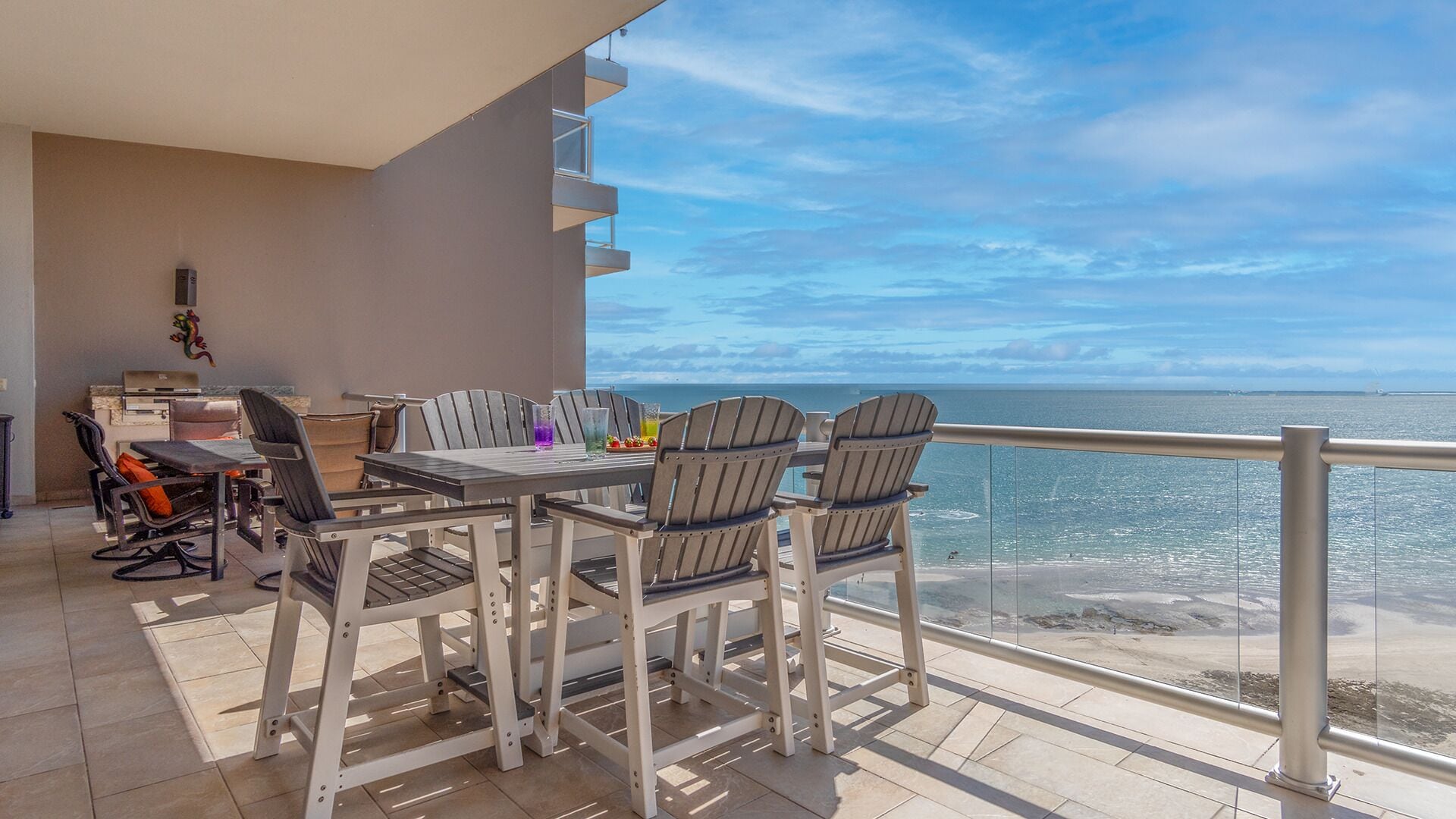 Ein Balkon mit Esstisch und Stühlen mit Blick auf einen Strand.