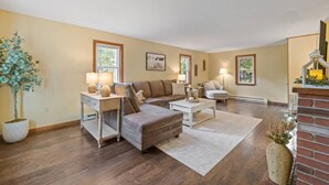 Una sala de estar con sofá, sillón, mesa de centro y chimenea.