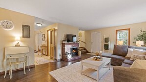 Una sala de estar con chimenea, televisor, sofá y una mesa de comedor.