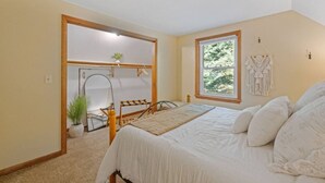 Un dormitorio con cama, ventana, planta y puerta que da a otra habitación.