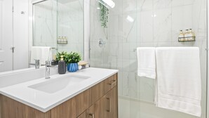 Un baño moderno con un espejo grande, un lavabo y una zona de ducha.