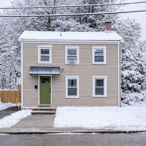 A two-story house with a green door, multiple windows, and a chimney. - Village Retreat • Hot Tub & Views (Saugerties)