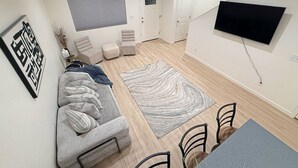 Una sala de estar moderna con un sofá gris, dos sillones, una mesa de centro y un televisor montado en la pared.