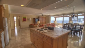 A spacious living area with a kitchen island, a dining area with a view, and a large window overlooking the ocean. - 3-bedroom Ocean Front PENTHOUSE in marvelous Cabo San Lucas (Cabo San Lucas)