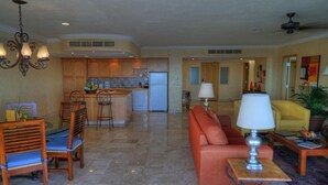 A spacious living area with a kitchen in the background, a dining set, and a sofa with a table lamp. - 3-bedroom Ocean Front PENTHOUSE in marvelous Cabo San Lucas (Cabo San Lucas)