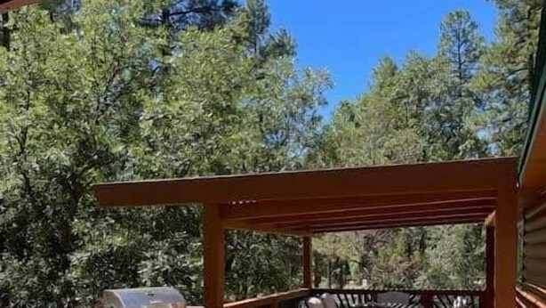 A wooden deck with outdoor furniture, including a table and chairs, and a grill.