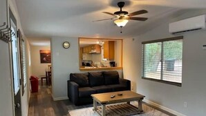 A living room with a ceiling fan, a sofa, a coffee table, and a window with blinds.