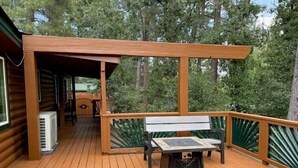A wooden deck with a covered seating area, a table, and a bench.