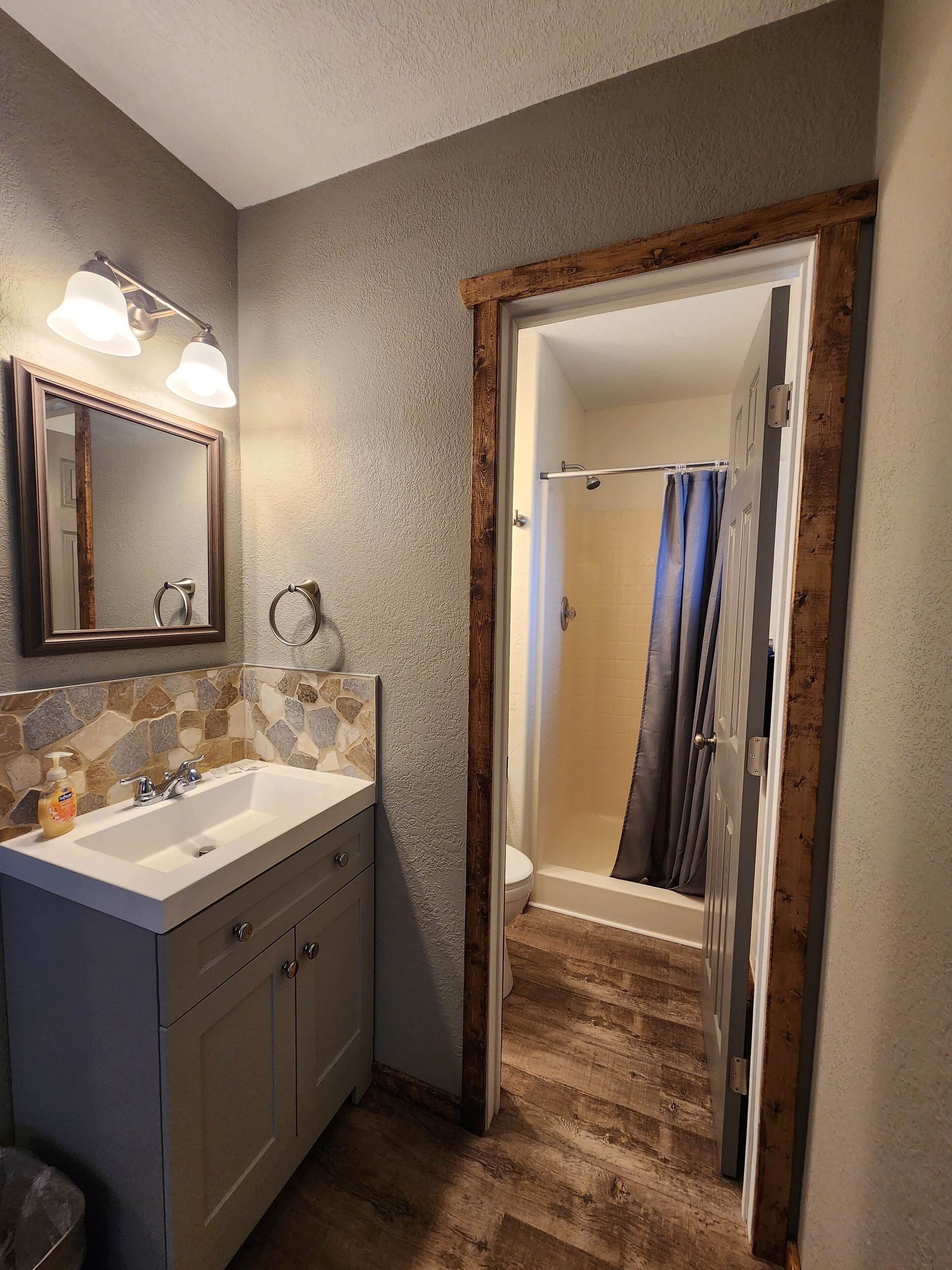 A bathroom with a double sink vanity, a mirror, and a shower with a curtain.