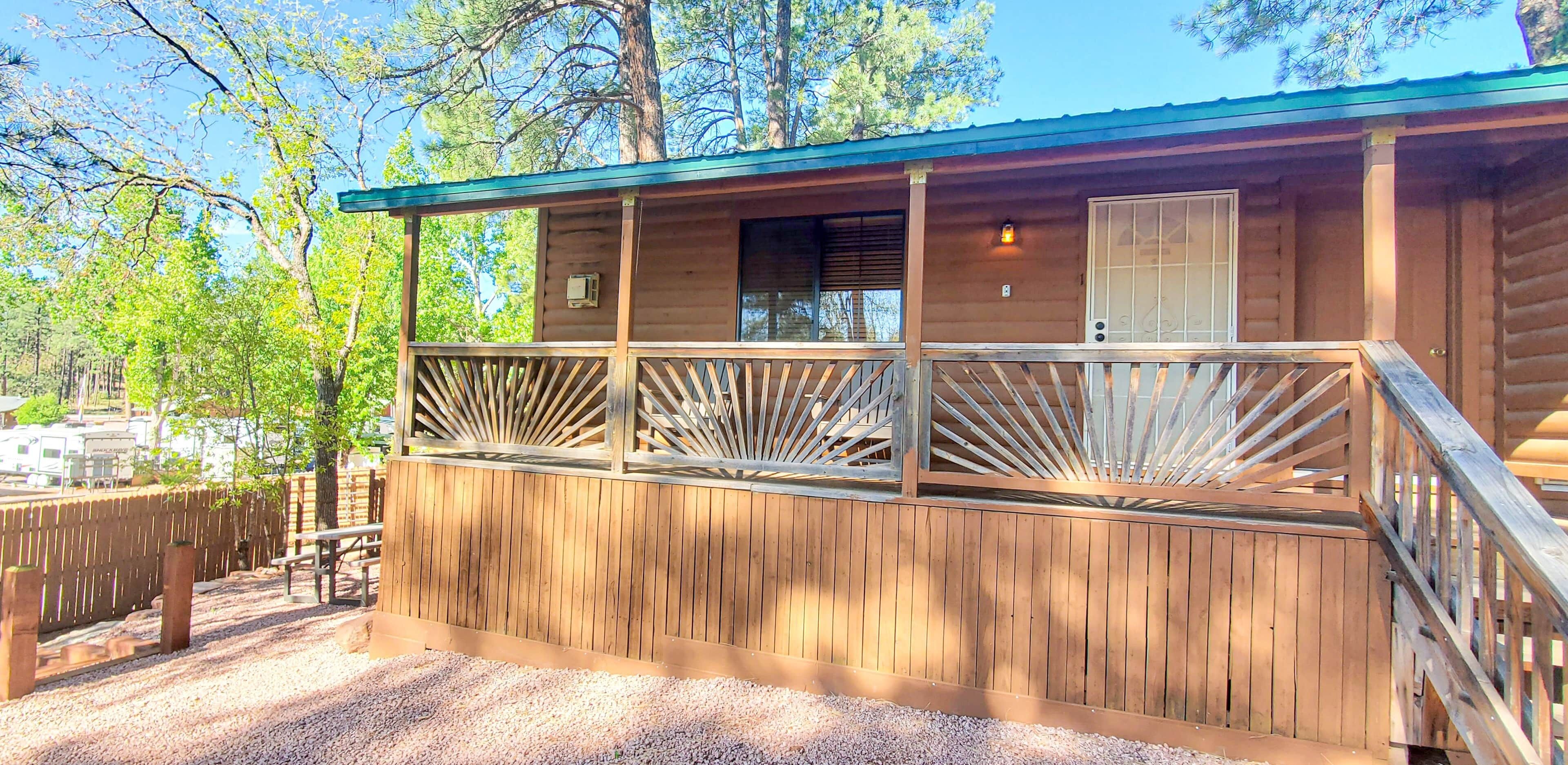 A wooden cabin with a balcony, a window, and a door.