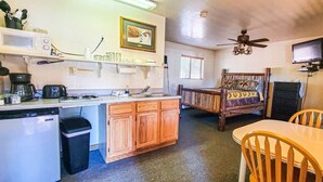 A compact kitchen with a microwave, coffee maker, and sink. There is a wooden dining table with chairs and a ceiling fan. - Elk Haven Cabins - Cabin 2 (Payson)