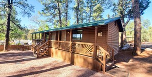 Une cabane en bois dotée d’un porche couvert et d’un escalier menant à l’entrée.