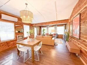 Une pièce spacieuse avec un intérieur en bois, une table à manger avec des chaises, un canapé, un banc et un luminaire suspendu.