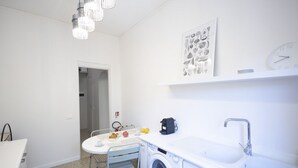 Ett kompakt kök med tvättmaskin, diskho och en matplats med bord och stolar.