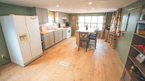 A compact kitchen with a refrigerator, stove, and dining table. - Paula's Place Near The Lake (Elephant Butte)